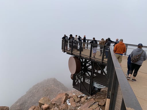 Pikes Peak Summit complex visitors walk on PermaTrak boardwalk hanging over mountain range